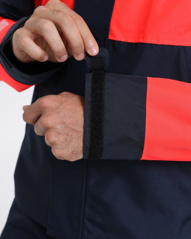 Adjustable hook-and-loop cuff tab on the sleeve of a navy and coral shell jacket